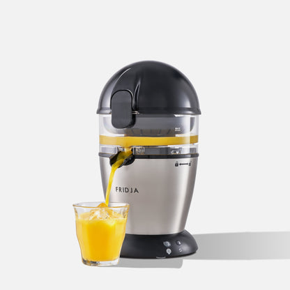The Fridja f900 Automatic Citrus Juicer - Refurbished Grade A, featuring a stylish stainless steel finish and black lid, pours fresh orange juice into an ice-filled glass against a plain white background.
