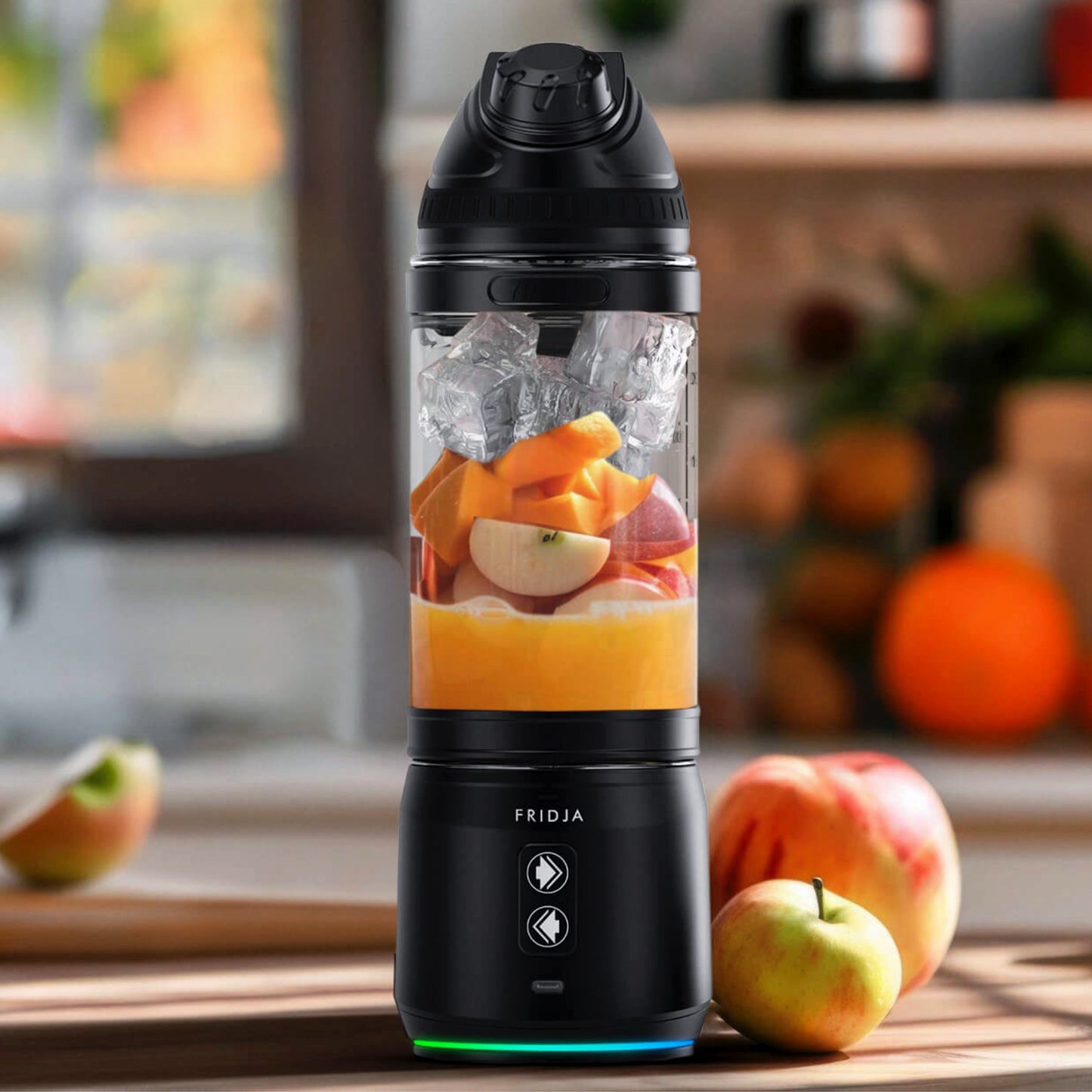 The Fridja f500 Portable Blender in black, ideal for smoothies and active lifestyles, sits on a kitchen counter filled with ice, orange, and apple pieces, surrounded by whole apples and blurred fruit in the background.